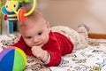 Adorable 6 months old little baby boy during tummy time surrounded by colourful toys Royalty Free Stock Photo