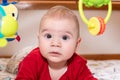 Adorable 6 months old little baby boy during tummy time surrounded by colourful toys Royalty Free Stock Photo