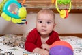 Adorable 6 months old little baby boy during tummy time surrounded by colourful toys Royalty Free Stock Photo