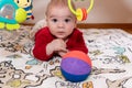 Adorable 6 months old little baby boy during tummy time surrounded by colourful toys Royalty Free Stock Photo