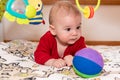 Adorable 6 months old little baby boy during tummy time surrounded by colourful toys Royalty Free Stock Photo