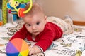 Adorable 6 months old little baby boy during tummy time surrounded by colourful toys Royalty Free Stock Photo