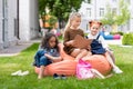 adorable multiethnic schoolgirls sitting on bean bag chair and reading book Royalty Free Stock Photo