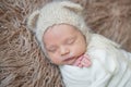 Child wrapped with white blanket, sleeping on furry surface