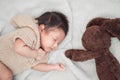 Adorable newborn baby peacefully sleeping with brown rabbit doll on a white blanket. Royalty Free Stock Photo