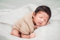 Adorable newborn baby peacefully sleeping on a white blanket.