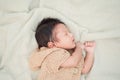 Adorable newborn baby peacefully sleeping on a white blanket.