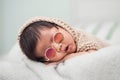 Adorable newborn baby peacefully sleeping on a white blanket. He is wearing sunglasses. Royalty Free Stock Photo