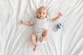 Adorable newborn baby wearing bodysuit lying on bed and looking at camera Royalty Free Stock Photo