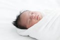 Adorable newborn baby wrapped in white swaddle towel lying on bed and sleeping peacefully. Sleeping infant in a wrap on white Royalty Free Stock Photo