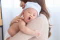 Adorable newborn baby yawn sleepy or cry on mom shoulder, young Asian beautiful mother hold infant 0-1 month with love, gently,