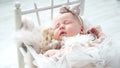 Adorable newborn girl in cute dress sleeps in small bed Royalty Free Stock Photo