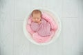 Adorable newborn girl lying in baby nest on light background