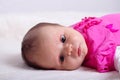 Adorable one month old baby girl in pink dress lies on a soft blanket