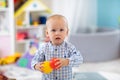 Adorable one year old baby in playroom. Child boy playing with colorful toys at home. Early development, learning and Royalty Free Stock Photo