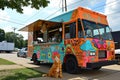 An adorable orange and white cat calmly sits in front of a vibrant food truck, capturing a whimsical moment, A food truck with its