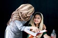 Adorable Pakistani girl with beautiful eyes wear hijab, learning Quran book with mother, Muslim family, daughter and mom read holy Royalty Free Stock Photo