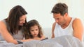 Adorable parents with her daughter on the bed