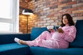 Adorable pregnant female enjoy watching tv at home