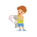 Adorable preschool boy holding bunny toy and eating tasty