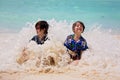 Adorable preschool children, boys, having fun on ocean beach. Excited children playing with waves, swimming, splashing happily