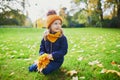 Adorable preschooler girl enjoying nice and sunny autumn day outdoors