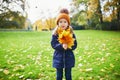 Adorable preschooler girl enjoying nice and sunny autumn day outdoors