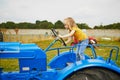 Adorable preschooler girl playing on old blue tractor on Gally farm near Paris, France