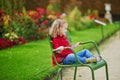 Adorable preschooler girl sitting on green chair in Tuileries garden in Paris, on a fall day