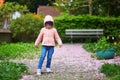 Adorable preschooler girl walking in cherry blossom garden, path is covered by pipnk fallen petals and flowers Royalty Free Stock Photo