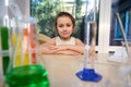 Preschooler girl sitting at table with glassware for chemistry lab ready for fascinating experiments in chemical class Royalty Free Stock Photo