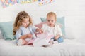 adorable preschooler and toddler sisters playing on bed