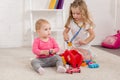 adorable preschooler and toddler sisters playing with first aid kit