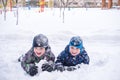 Adorable preschooler in winter wear sit amoung snow and play wit