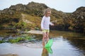 Adorable preshooler girl playing with scoop net on the beach at Atlantic coast of Brittany, France