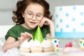 Adorable preteen sitting at table and looking at cupcakes during birthday celebration at home.