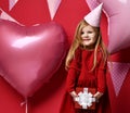 Adorable pretty girl with pink balloons and red present gift and birthday cap Royalty Free Stock Photo