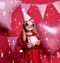 Adorable pretty girl with pink balloons and red present gift and birthday cap Royalty Free Stock Photo