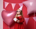 Adorable pretty girl with pink balloons and red present gift and birthday cap Royalty Free Stock Photo