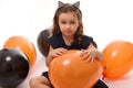 4 y.o adorable pretty little girl in witch costume plays with black and orange balloons isolated on white background. Concept of a Royalty Free Stock Photo