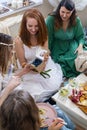 Adorable redhead woman taking wrapped gift box celebrating birthday in modern hippie bohemian style