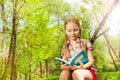 Adorable relaxed girl reading a book outdoor