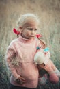 Adorable sad girl with hourse toy in park