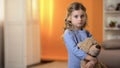 Adorable sad little girl hugging favorite teddy bear feeling lonely in orphanage Royalty Free Stock Photo