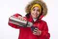 Horizontal portrait of a cute school-age boy winter traveler adventurer pouring hot drink from thermos into mug smiling toothy