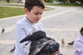 Adorable schoolboy feeding feral pigeons in the park. The concept of care, kindness and love for wild animals Royalty Free Stock Photo