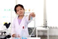 Adorable schoolgirl in lab coat doing simple science experiments, young Asian kid scientist showing tube and having fun Royalty Free Stock Photo