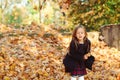 Adorable schoolgirl walking in autumn park after school. Beautiful child girl throwing autumn leaves Royalty Free Stock Photo
