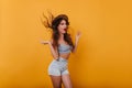 Adorable shapely girl in summer outfit posing with pleasure in studio. Indoor photo of excited long-haired woman in hat