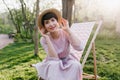 Adorable short-haired lady playfully posing in forest, sitting in comfortable recliner on grass background. Outdoor